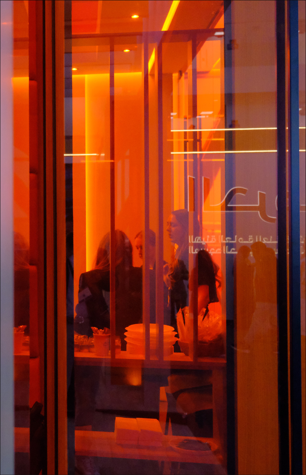 Visitors and reflections through orange meeting-room glass